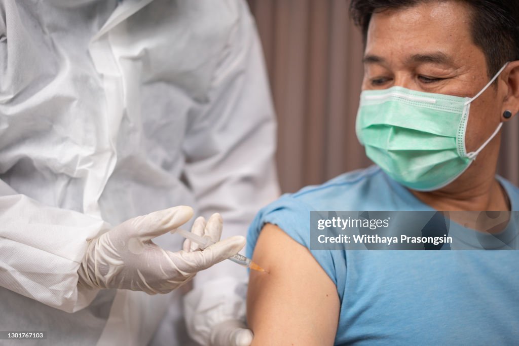 Male senior patient getting vaccinated at medical clinic during coronavirus pandemic.