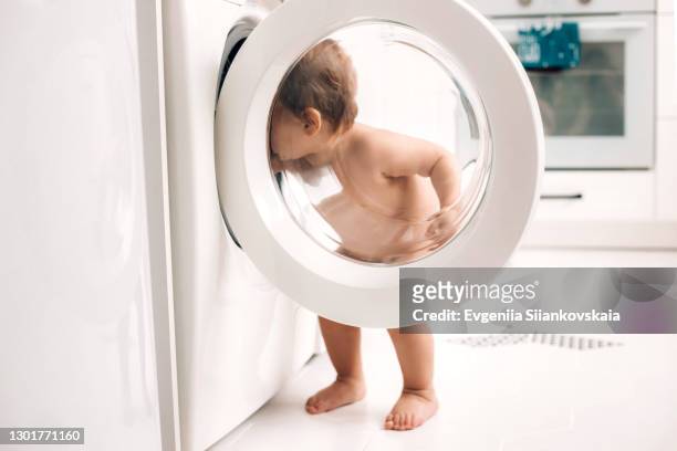 cute baby standing near washer on the kitchen. - children circle floor stock pictures, royalty-free photos & images