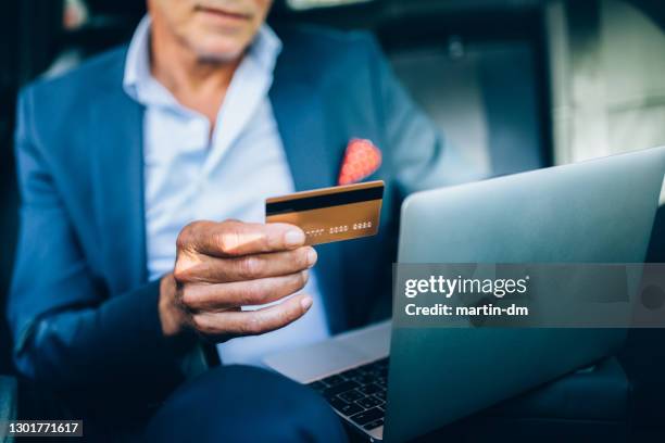 businessman in taxi making online reservation with credit card - formalwear stock pictures, royalty-free photos & images