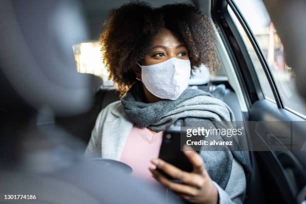 businesswoman traveling by taxi during covid-19 pandemic - taxi stock pictures, royalty-free photos & images