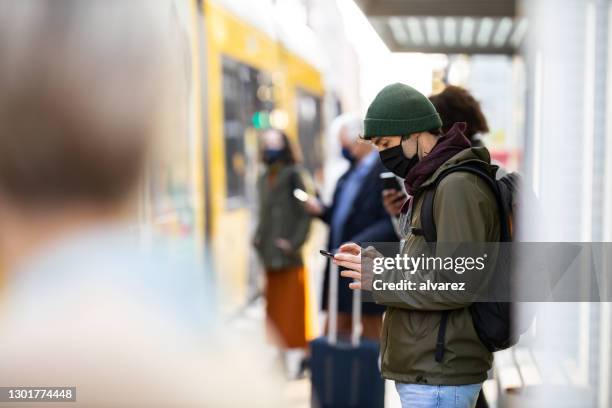 young man waiting at city tram station during pandemic - germany covid stock pictures, royalty-free photos & images