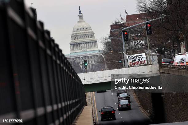 With the U.S. Capitol in the distance, a sign saying, "Convict Or Be Complicit" hangs on a bridge over North Capitol Street on February 12, 2021 in...