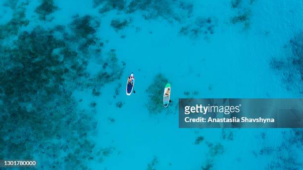 vista aérea escénica de la mujer y el hombre flotando en la tabla de paddle en el océano de color turquesa en la isla de zanzíbar, tanzania - zanzibar fotografías e imágenes de stock