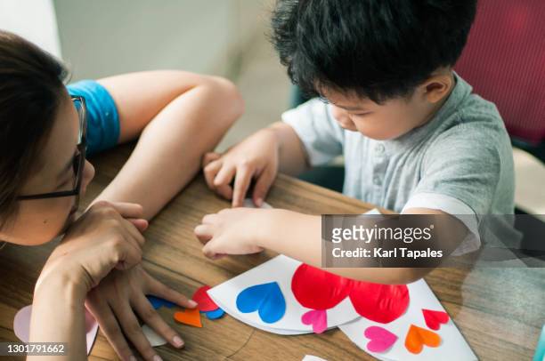 mother and son doing art and craft at home in preparation for valentines day - philippines family celebration stock pictures, royalty-free photos & images
