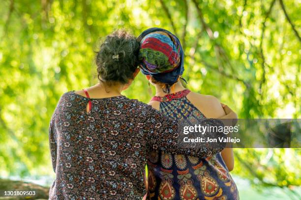 a woman sitting next to her sister who has cancer. she is wearing a headscarf. - cancer survivor stock pictures, royalty-free photos & images