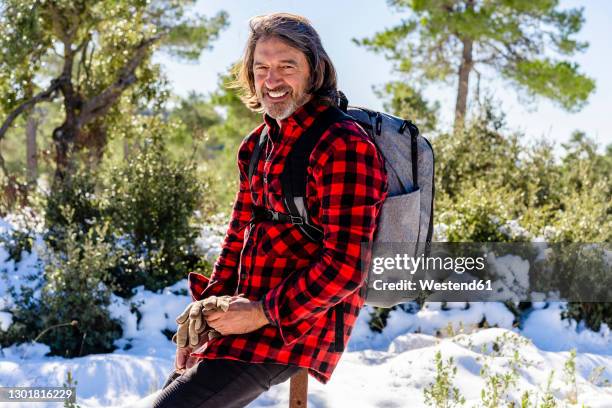 male hiker smiling while resting on pole in forest - hiking pole stock-fotos und bilder