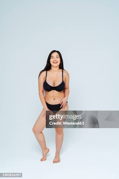 young woman wearing black lingerie smiling while standing in studio - beautiful voluptuous women stock pictures, royalty-free photos & images