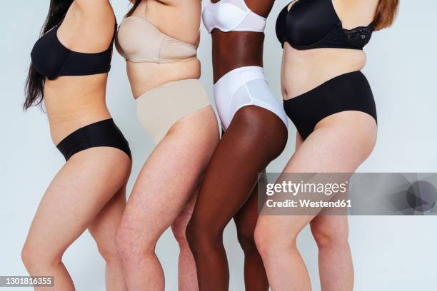 young women wearing lingerie standing in a line against white background - body positive stockfoto's en -beelden
