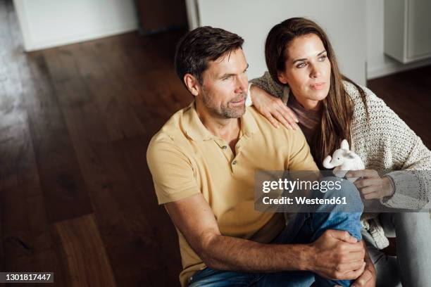 mature woman holding elephant stuffed toy while day dreaming with man in apartment - elephant at home stockfoto's en -beelden