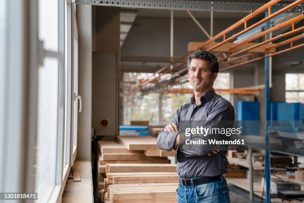 portrait of carpenter posing in production hall with crossed arms - gray shirt stock pictures, royalty-free photos & images