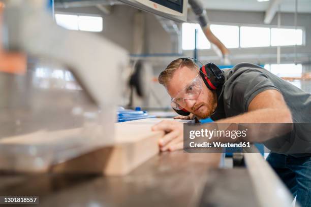 portrait of carpenter cutting plank of wood - kreissäge stock-fotos und bilder