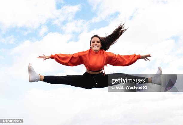 portrait of beautiful brunette jumping against sky - crop top stock pictures, royalty-free photos & images