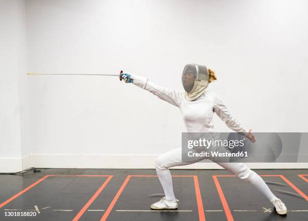 womanin fencing outfit practicing at gym - escrime photos et images de collection