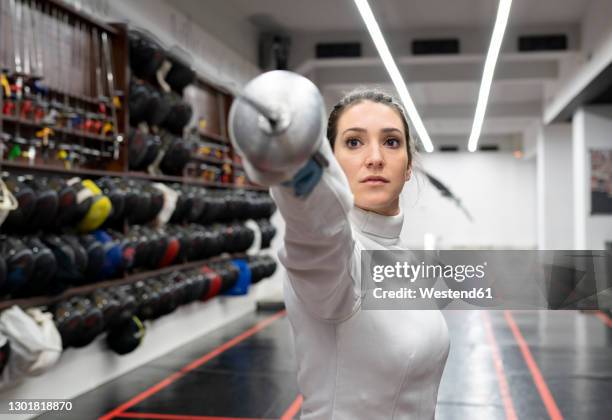 womanin fencing outfit practicing at gym - fechten stockfoto's en -beelden