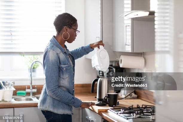 woman pouring water into kettle in kitchen - 浄水 ストックフォトと画像