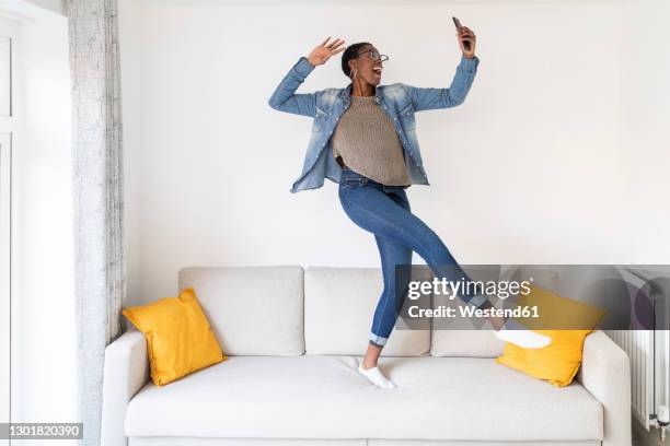 woman dancing on sofa - frau tanzt im wohnzimmer stock-fotos und bilder