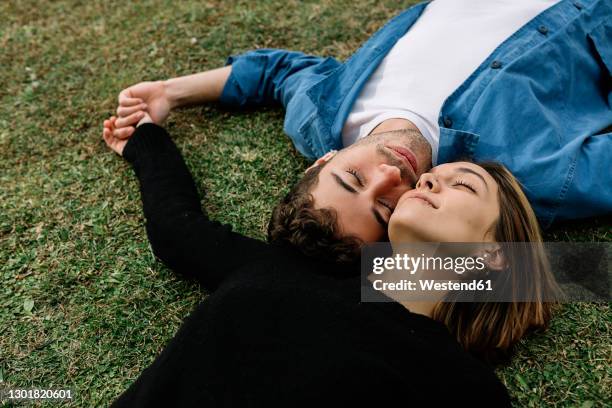 smiling couple lying on lawn - 面貼面 個照片及圖片檔