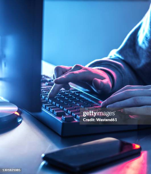 hands of teenage boy hacking computer on desk - deep web - fotografias e filmes do acervo