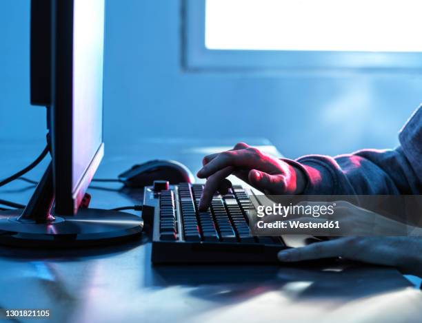 hands of teenage boy breaching data from computer on desk - deep web 個照片及圖片檔