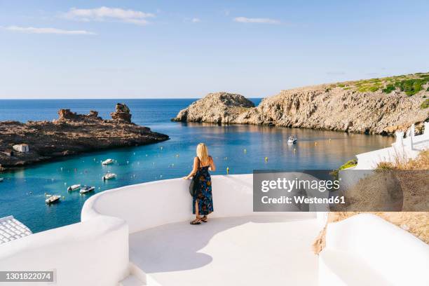 mature woman looking at sea while standing on terrace against sky - menorca stockfoto's en -beelden