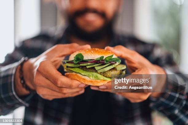 hombre sosteniendo hamburguesa vegana de garbanzo en la mano - vegan food fotografías e imágenes de stock