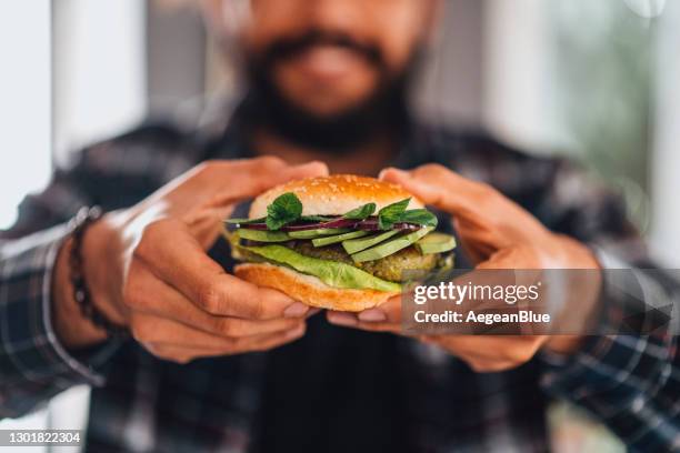 homem segurando hambúrguer de grão-de-bico vegano na mão - hamburger - fotografias e filmes do acervo