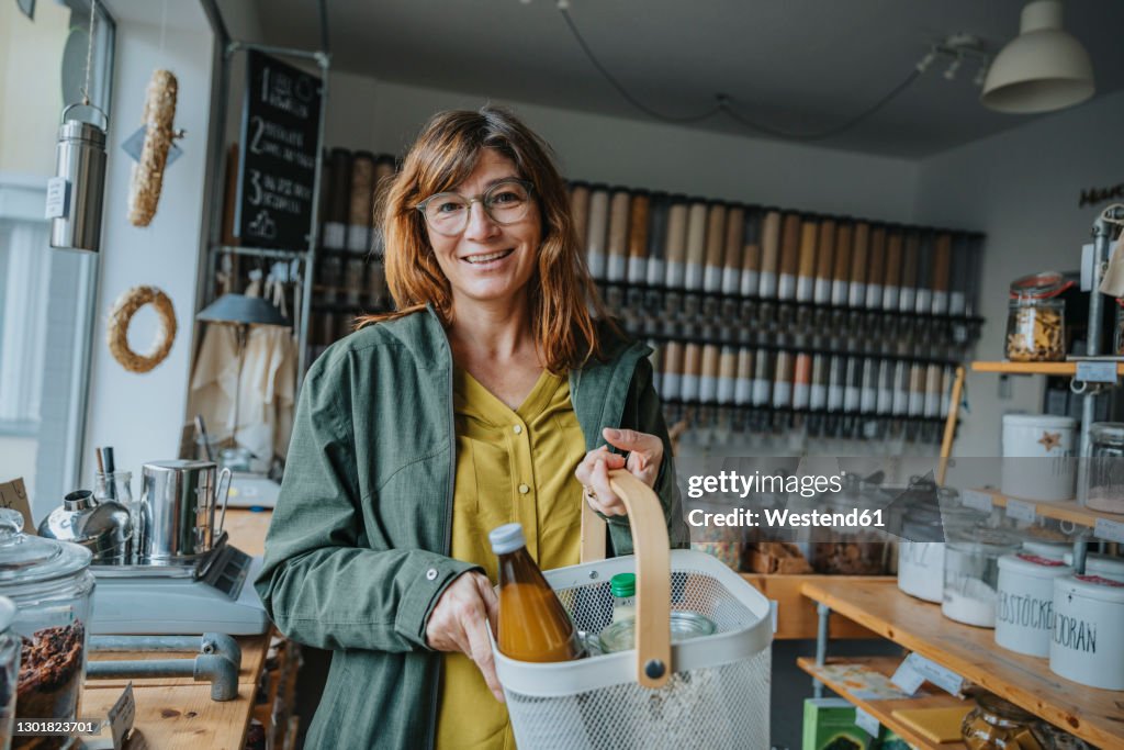 Happy mature female customer wearing eyeglasses shopping groceries in retail store