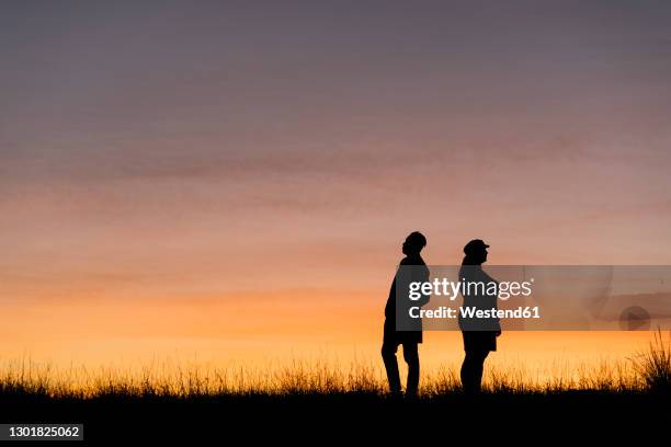 in silhouette of man and woman standing against sky - standing apart stock pictures, royalty-free photos & images