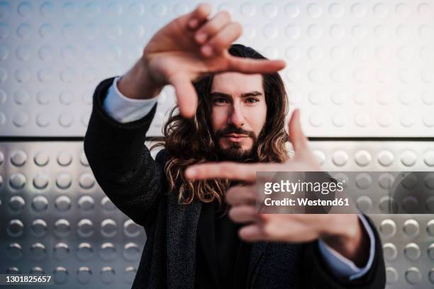 businessman making finger frame while standing against silver wall - hand on hip bildbanksfoton och bilder