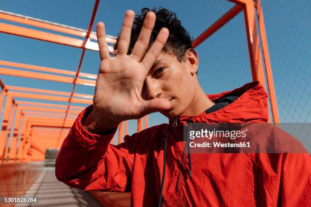 close-up of young man showing stop sign against clear sky - cool attitude stockfoto's en -beelden
