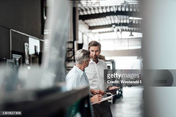 entrepreneur holding digital tablet while having discussion with colleague at industry - selective focus stock-fotos und bilder