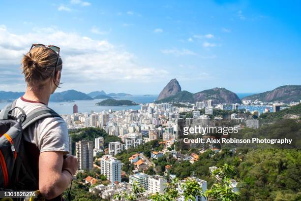 a young man hiking and looking out over the rio de janeiro skyline - rio de janeiro skyline stock pictures, royalty-free photos & images