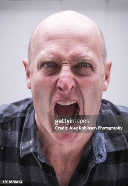 head shot of a bald man in his fifties shouting - angry bald screaming man ストックフォトと画像