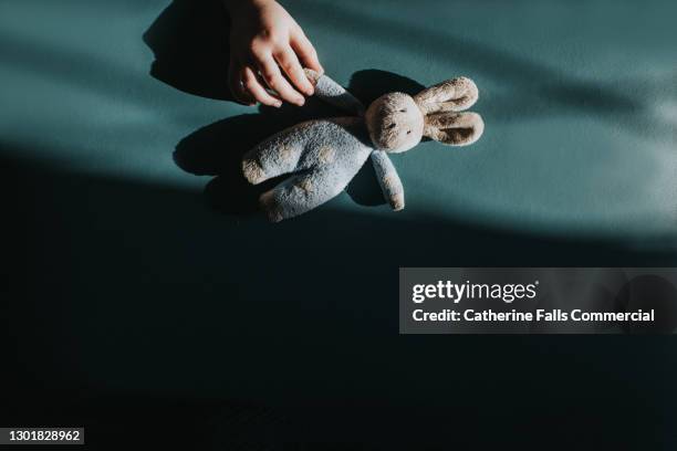 child's hand reaches for a small toy bunny - animal friendship stock pictures, royalty-free photos & images