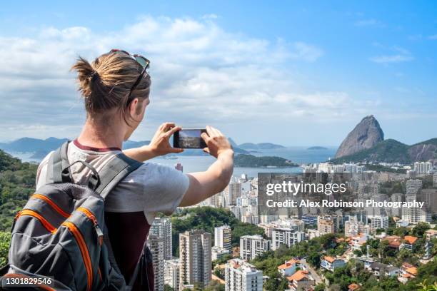 a young man taking shots of the rio de janeiro skyline with a smart phone - rio de janeiro skyline stock pictures, royalty-free photos & images