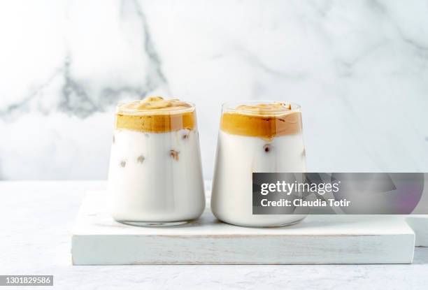 two glasses of dalgona coffee on cutting board on white background - dalgona 個照片及圖片檔