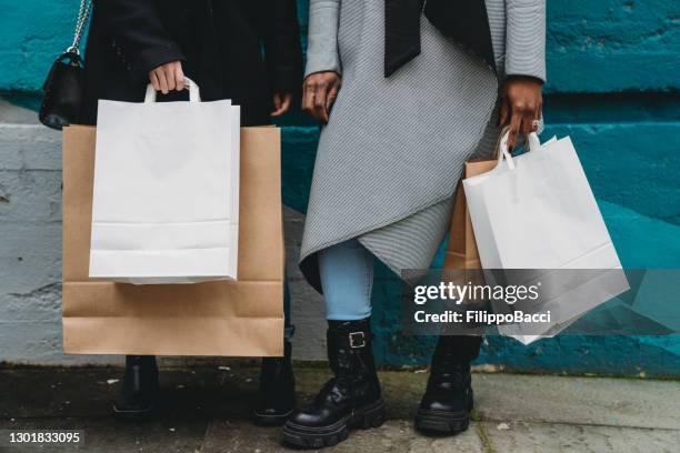 detail of the shopping bags of two friends against a blue wall - gen z shopping stock pictures, royalty-free photos & images