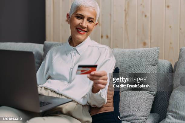 happy senior woman using a credit card to pay for her online order - click and collect stock pictures, royalty-free photos & images