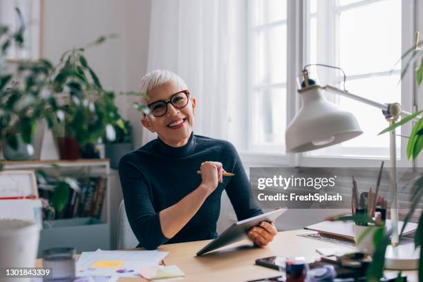 porträt einer lächelnden oberbauingenieurin, die in ihrem büro an einem projekt arbeitet - desk woman glasses stock-fotos und bilder