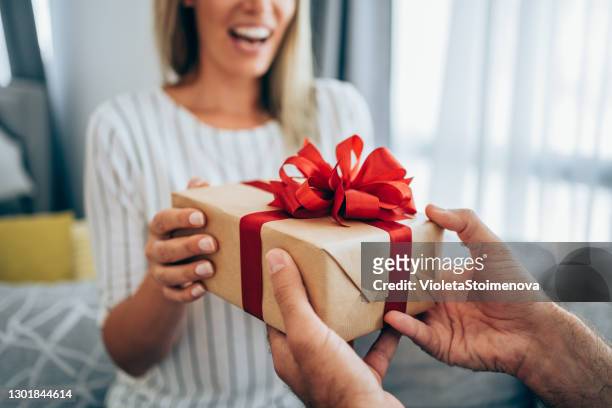 joven alegre recibiendo un regalo de su novio. - dar fotografías e imágenes de stock