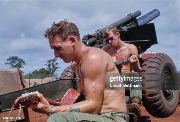 Officers of the United States Army's 11th Armoured Cavalry - one with a tattoo of the Playboy logo - playing guitars and relaxing on a Howitzer...