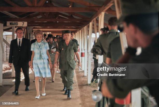 United States First Lady Pat Nixon , wearing a blue-and-white two-piece skirt suit, is escorted by military personnel during a visit to the 24th...