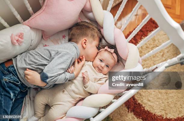 brother and sister lying together in crib - kiss sisters stock pictures, royalty-free photos & images