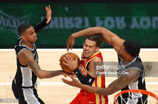 Trae Young of the Atlanta Hawks draws a foul from Rudy Gay of the San Antonio Spurs during the first half at State Farm Arena on February 12, 2021 in...