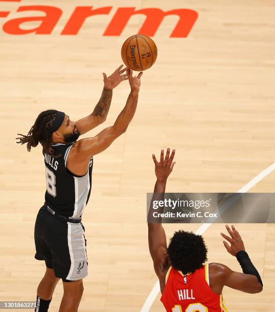 Patty Mills of the San Antonio Spurs shoots a three-point basket and draws a foul from Solomon Hill of the Atlanta Hawks during the second half at...