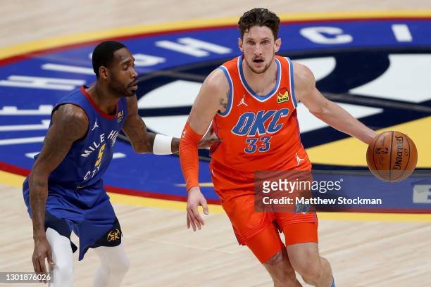 Mike Muscala of the Oklahoma City Thunder drives against Will Barton of the Denver Nuggets in the third quarter at Ball Arena on February 12, 2021 in...