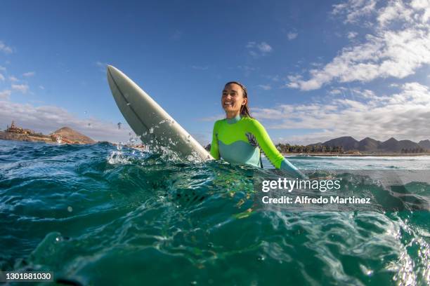 Surfer poses for a portrait with her surfboard into the sea as part of the sport activities practiced in the town of Todos Santos on February 11,...