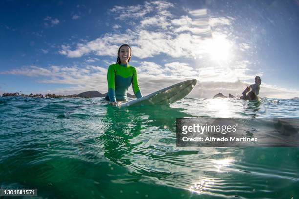 Surfer poses for a portrait with her surfboard into the sea as part of the sport activities practiced in the town of Todos Santos on February 11,...
