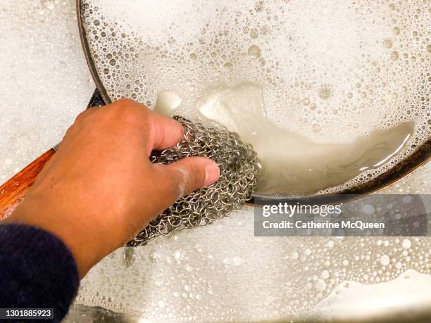 sustainable living: african-american woman cleaning dirty cooking pan with reusable stainless steel mesh - brillos stockfoto's en -beelden