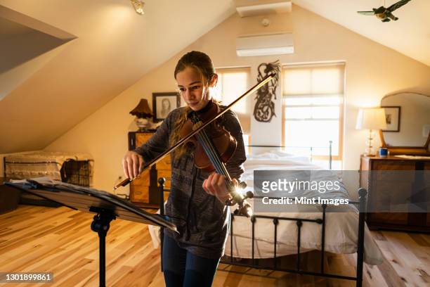 teenage girl playing her violin in her bedroom - muziekstandaard stockfoto's en -beelden